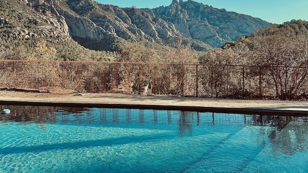 A clear blue pool with a mountain backdrop. - Hotel Masia Can Farrés (El Bruc)