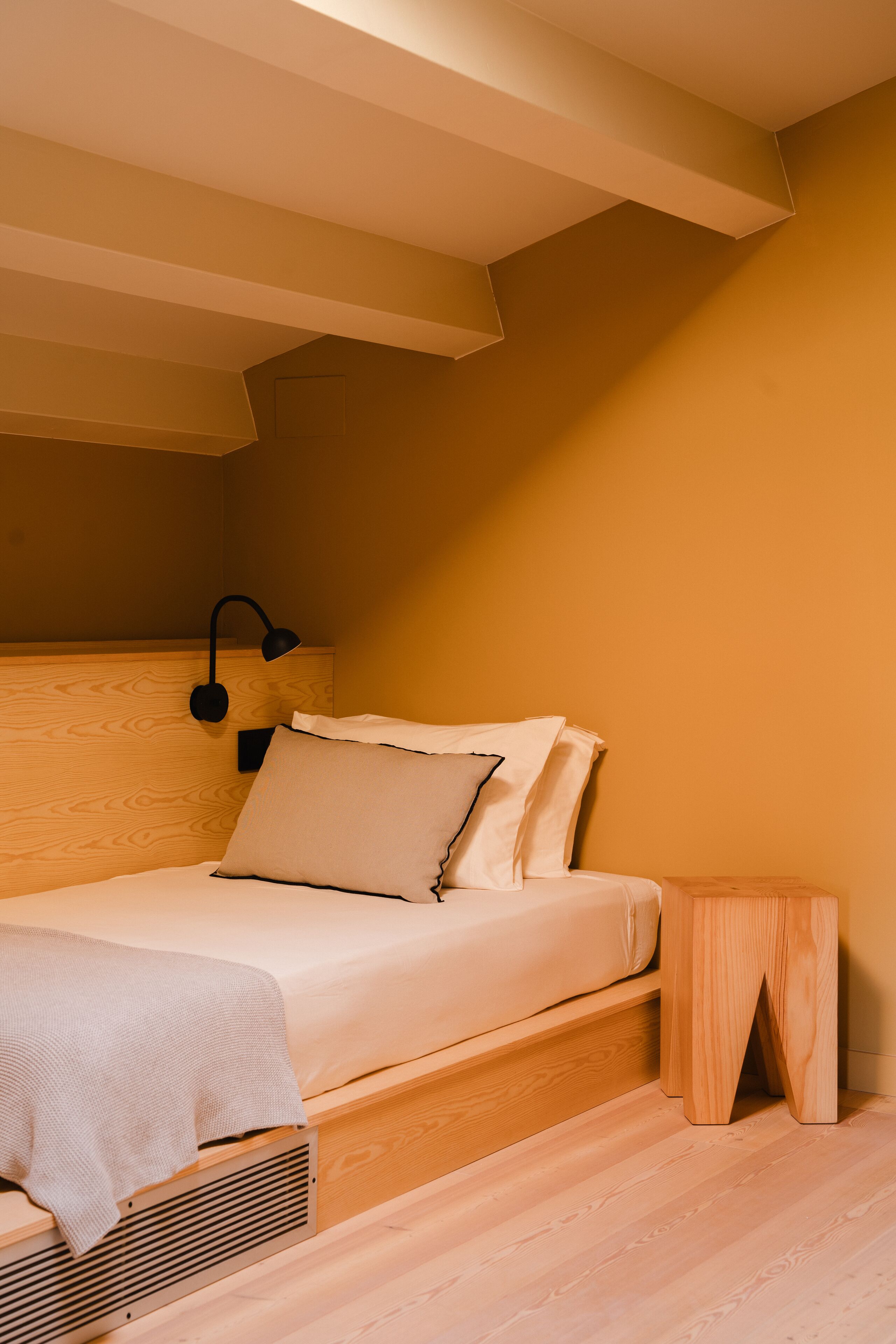 Un dormitorio con cabecera de madera, una mesita de noche y una cama con ropa de cama blanca.