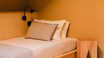 Un dormitorio con cabecera de madera, una mesita de noche y una cama con ropa de cama blanca.