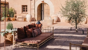 An outdoor seating area with a woven canopy, a wooden bench, and a cushioned sofa. - Hotel Masia Can Farrés (El Bruc)