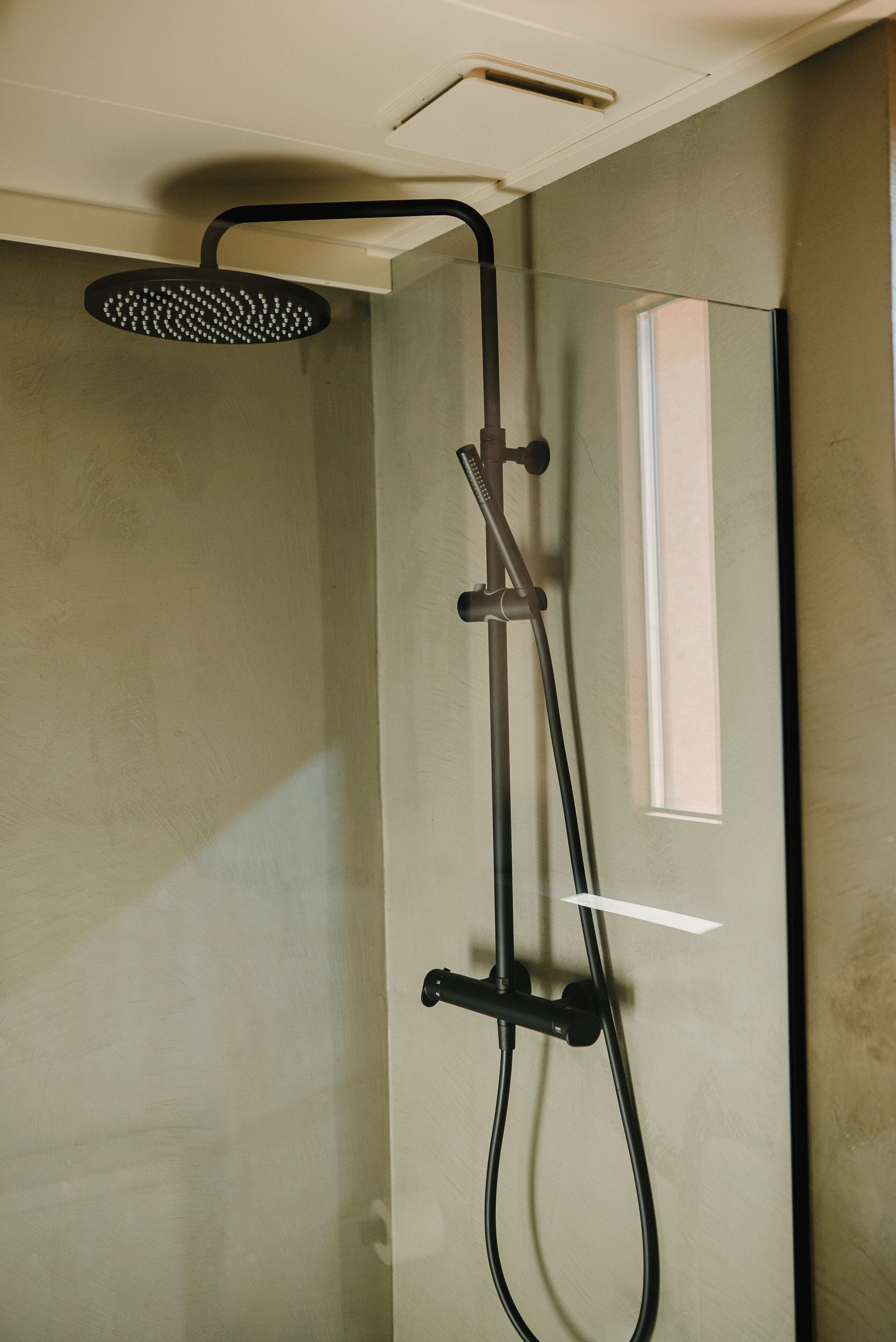 A shower with a handheld showerhead and a handheld shower attachment.