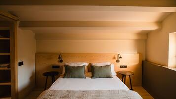 Un dormitorio con una cama grande, dos mesitas de noche, un cabecero de madera y un taburete pequeño.