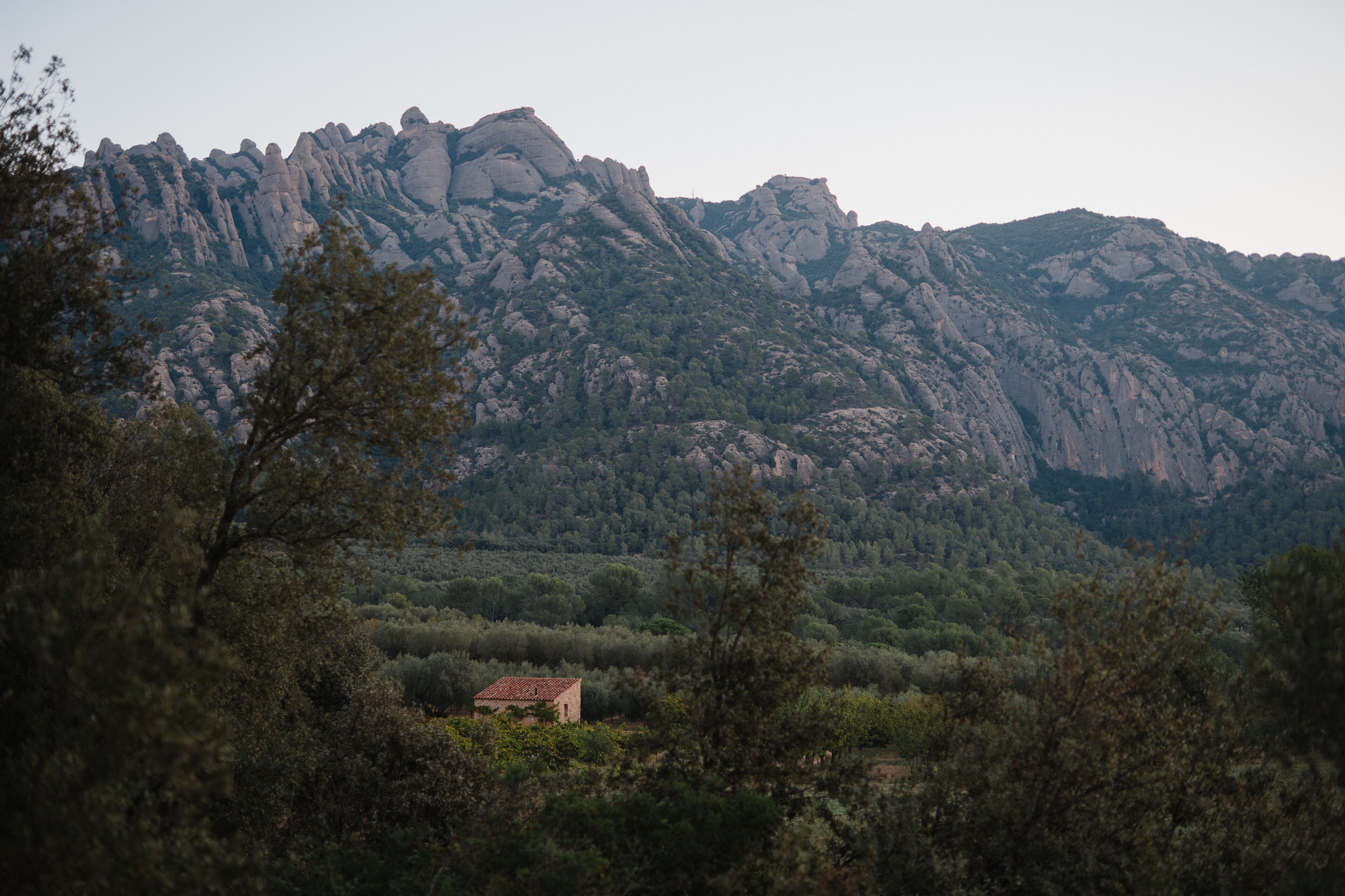 A mountainous landscape with a small building in the foreground.