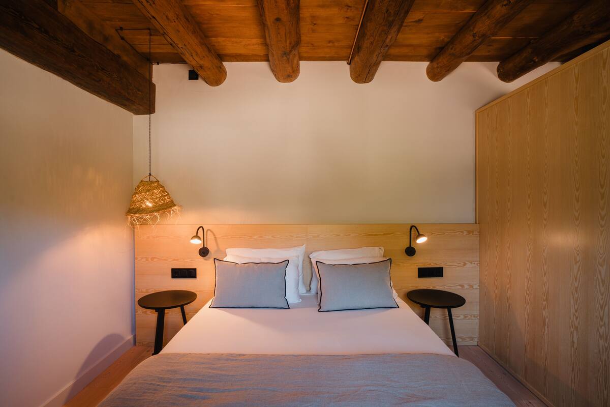 A bedroom with a wooden headboard, two bedside tables, and a hanging light fixture.