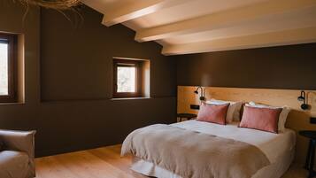 A bedroom with a large bed, a small window, and a wooden ceiling.