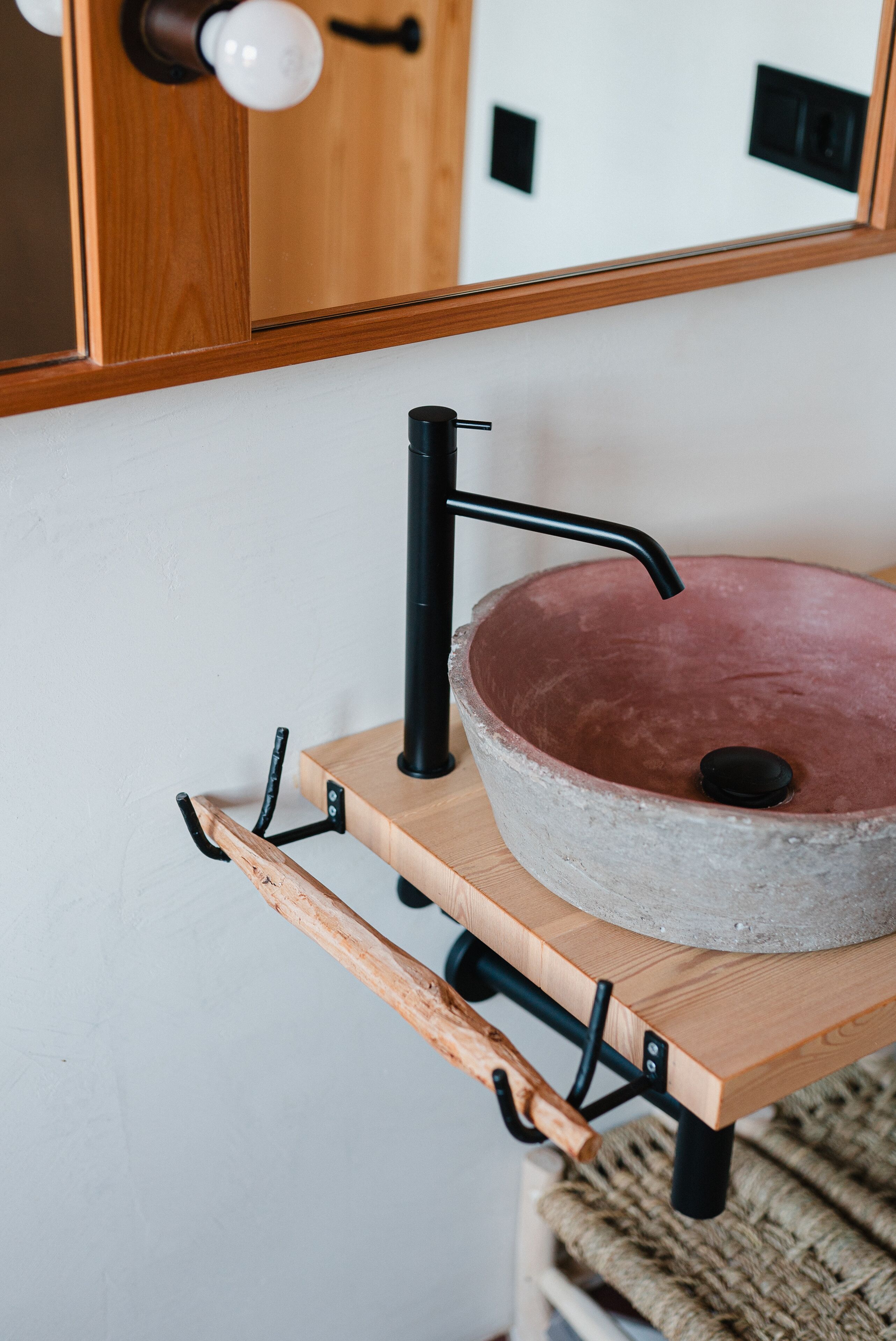 Un baño con tocador de madera, un lavabo de piedra redonda y un espejo sobre el lavabo.