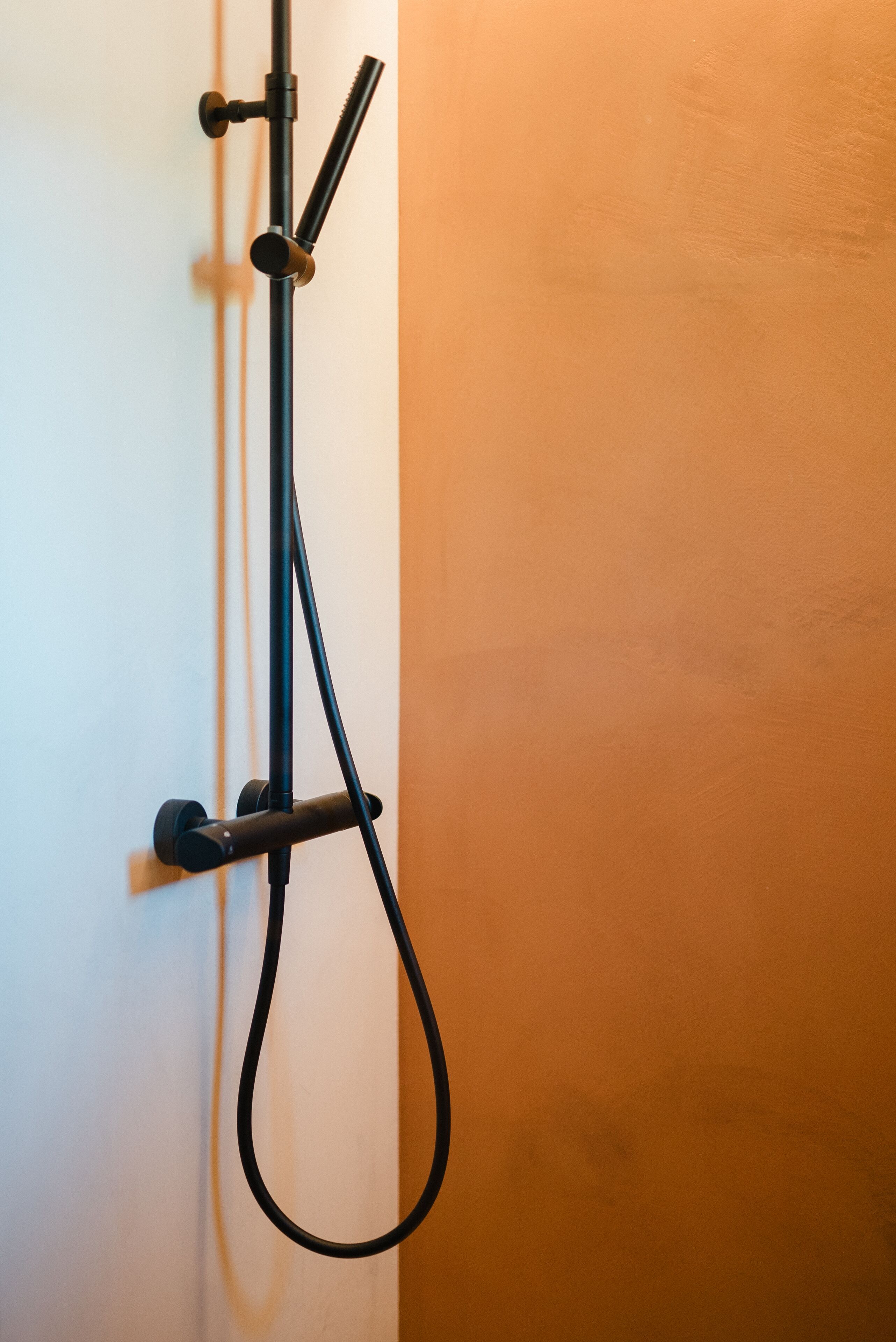 A black showerhead mounted on a white wall.