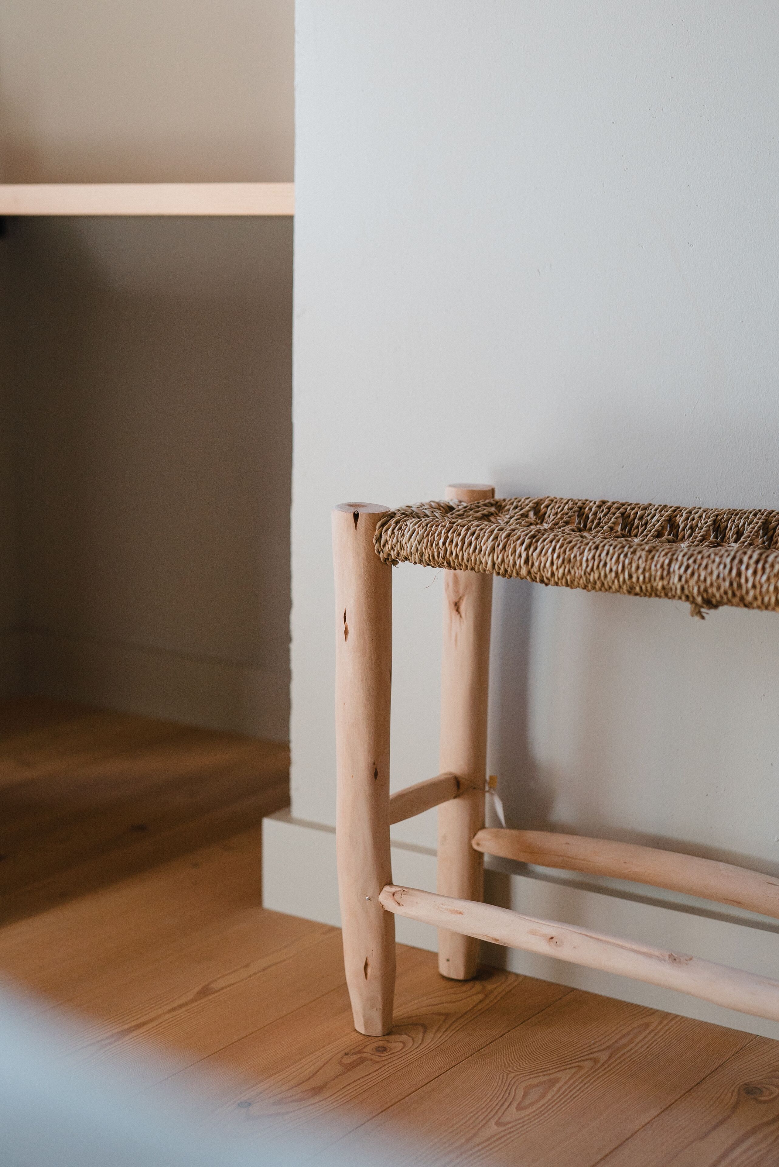 A wooden chair with a woven seat against a white wall.