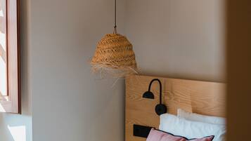 Een slaapkamer met een bed, een hangende geweven lamp, een nachtkastje en een bedtafel.