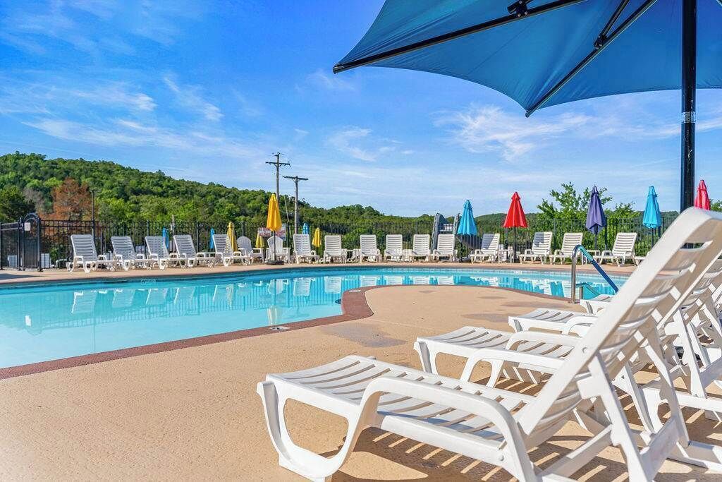 A pool area with white lounge chairs and umbrellas.