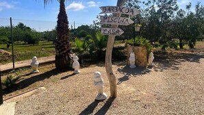 Un panneau indicateur en bois indiquant la direction de différents lieux, tels que le parking, l’espace barbecue, la piscine et la maison.
