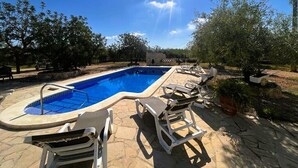 Une piscine avec des chaises longues et une terrasse en pierre.