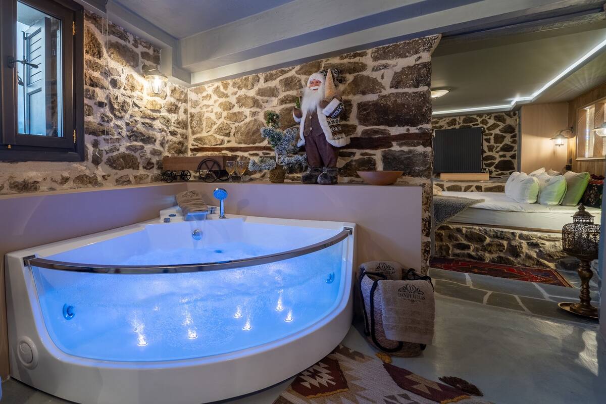 A modern bathroom with a large, illuminated bathtub, a stone wall, and a decorative gnome figure.