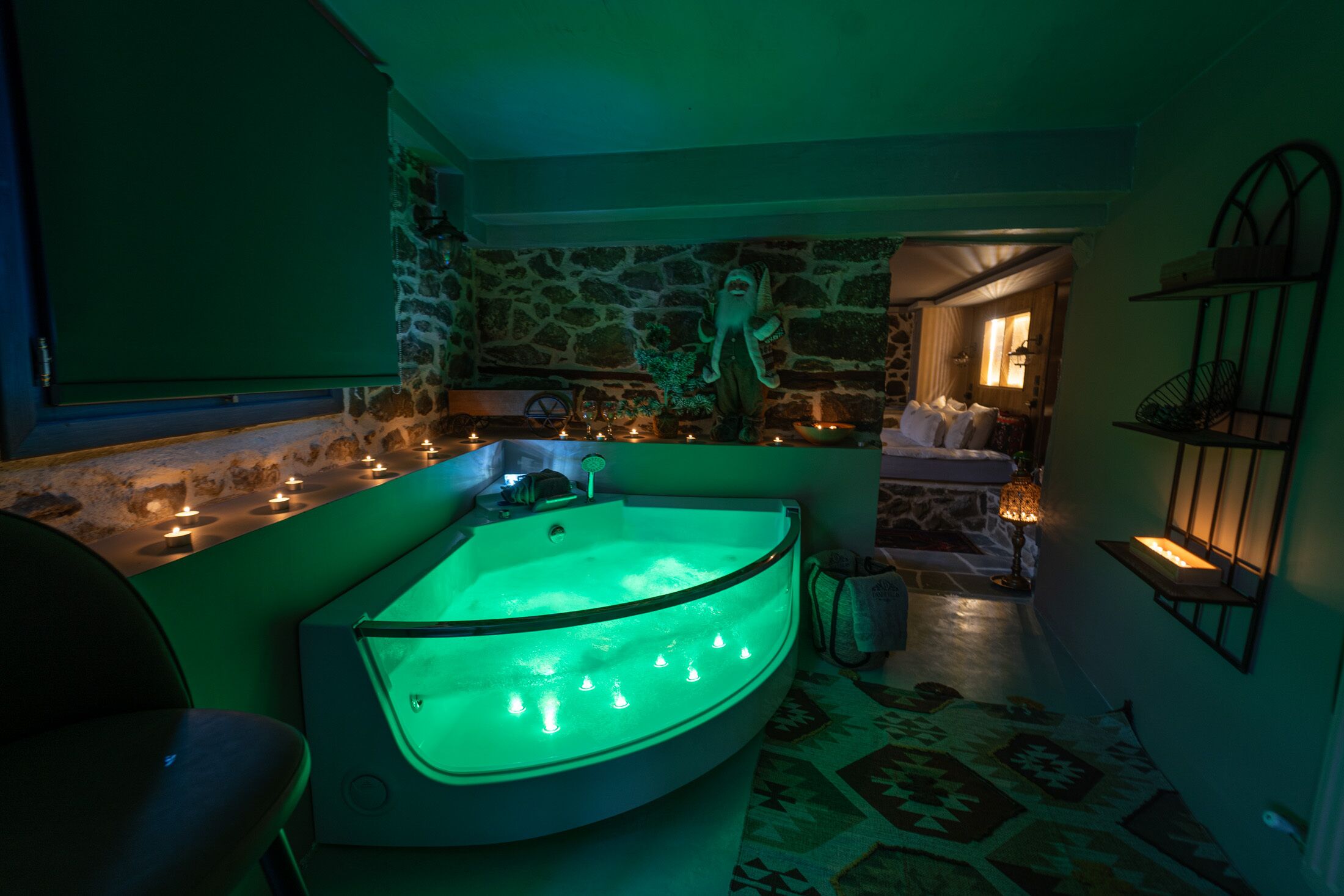A spa room with a curved bathtub, stone walls, and a green ambient light.