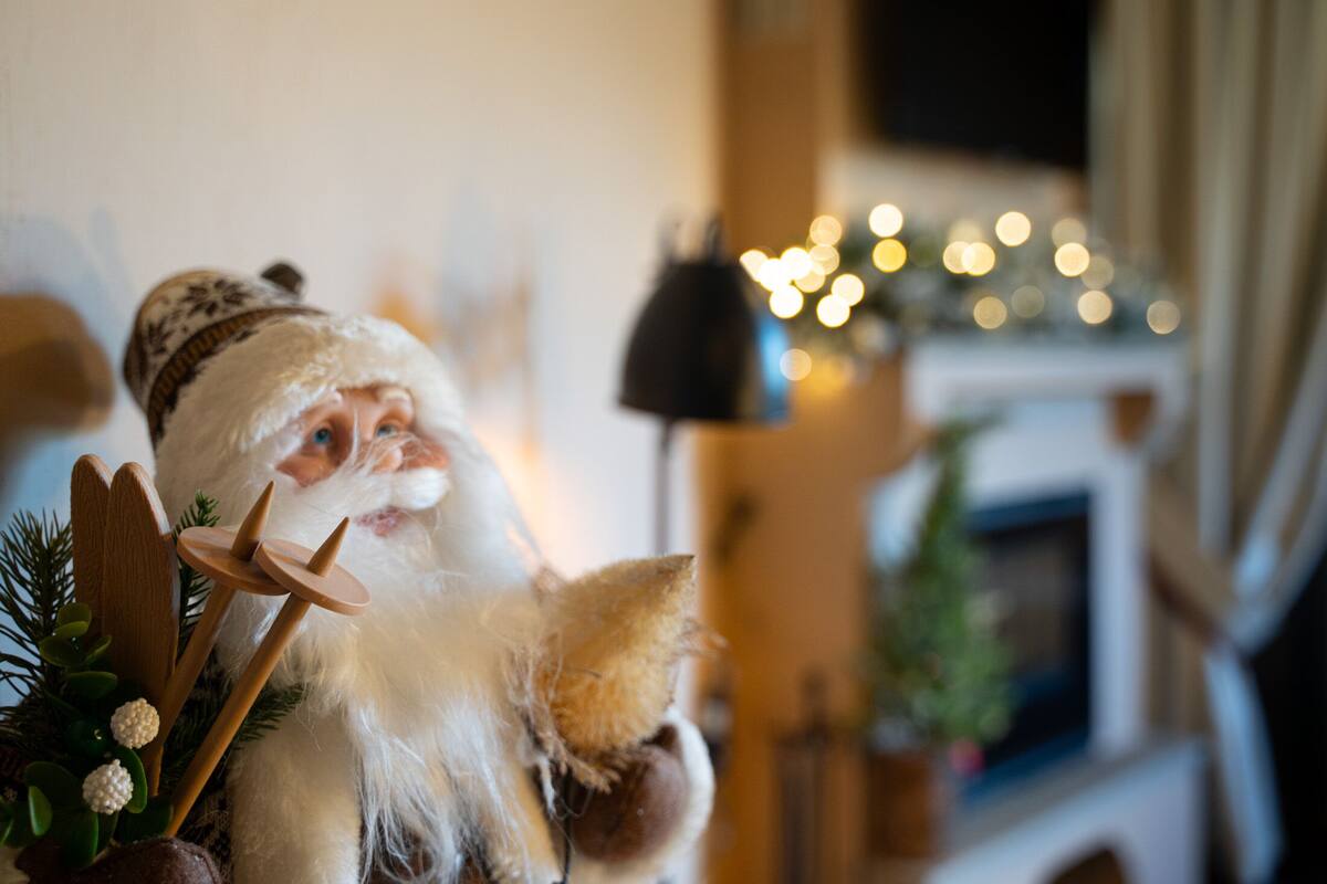 A room with a fireplace, a Christmas tree, and a decorative Santa Claus figure.