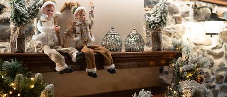 A cozy fireplace area with a bench, decorative figurines, and a stone wall backdrop.