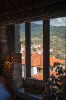 Vista a través de una ventana que muestra un interior rústico, con un banco de madera y una mesa pequeña con un marco de fotos.