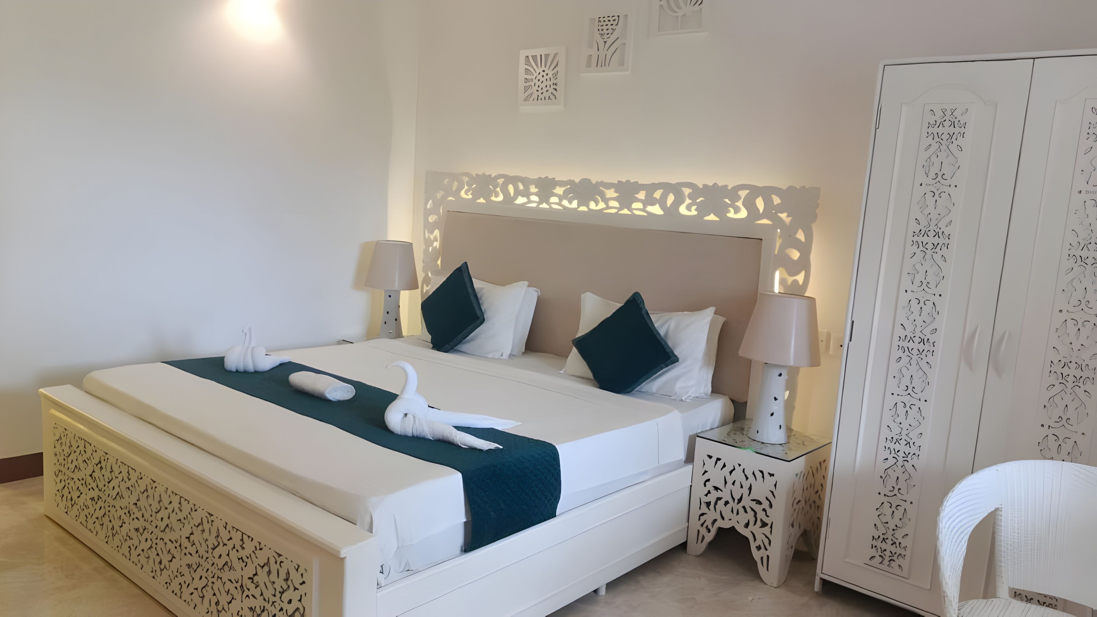 A neatly arranged bedroom with a bed, bedside tables, a wardrobe, and decorative wall panels.