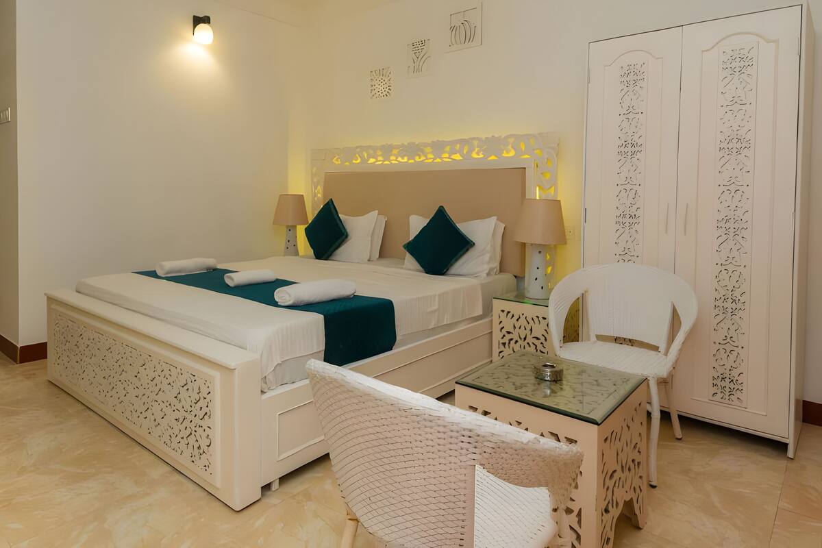 A hotel room with a bed, bedside tables, a chair, and a wardrobe.