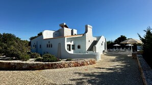 A white building with a tiled roof, a stone wall, and a cobblestone path. - Mourisca by Check-in Portugal (Vilamoura)