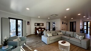A spacious living room with a sectional sofa, a dining area with a wooden table and chairs, and a kitchen in the background. - Mourisca by Check-in Portugal (Vilamoura)