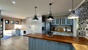 A modern kitchen with blue cabinets, a wooden countertop, and pendant lighting. - Mourisca by Check-in Portugal (Vilamoura)