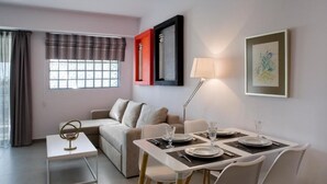 A modern living room with a dining area, a sofa, a coffee table, and a lamp. - SynAthens Apartments & Studios (Athens)