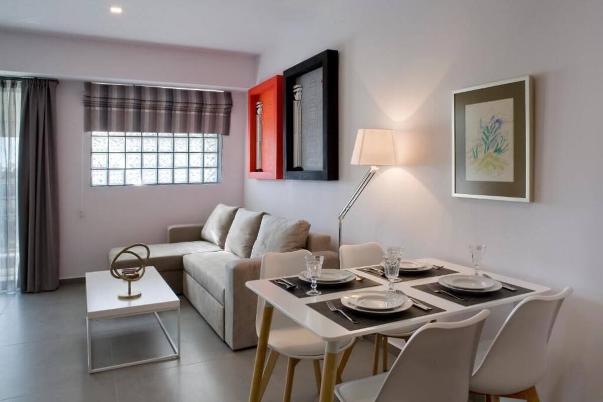 A modern living room with a dining area, a sofa, a coffee table, and a lamp.