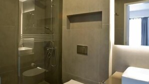 A modern bathroom with a glass-enclosed shower, a toilet, and a vanity with a mirror. - SynAthens Apartments & Studios (Athens)