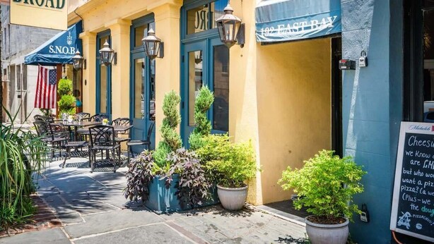 A street view of a restaurant with outdoor seating, a blue awning, and a sign reading "East Bay." - Luxury French Quarter 1bd Suite w. Parking (Charleston)