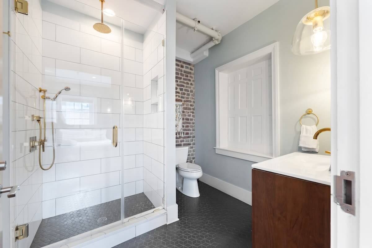 A bathroom with a glass-enclosed shower, a white toilet, and a wooden vanity.