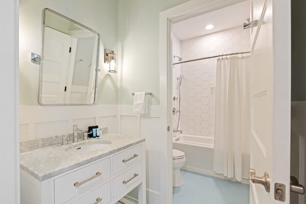 Un baño moderno con un lavabo de mármol, un inodoro y una ducha con puerta de cristal.