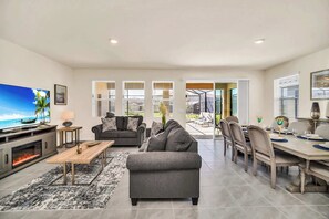 Una sala de estar moderna con chimenea, un televisor y un comedor con mesa preparada para cuatro.