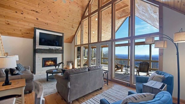 Una sala de estar amplia con chimenea, ventanas grandes y vistas al exterior.