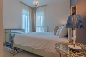 Une chambre d’hôtel avec un lit, une table de chevet avec une lampe, une commode et une vue sur les bâtiments par la fenêtre.