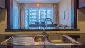 A modern kitchen with a double sink, a window with curtains, and a view of the cityscape. - Bella Vista - 29 Boulevard Downtown - 2BR - Partial Fountain View (Dubai)
