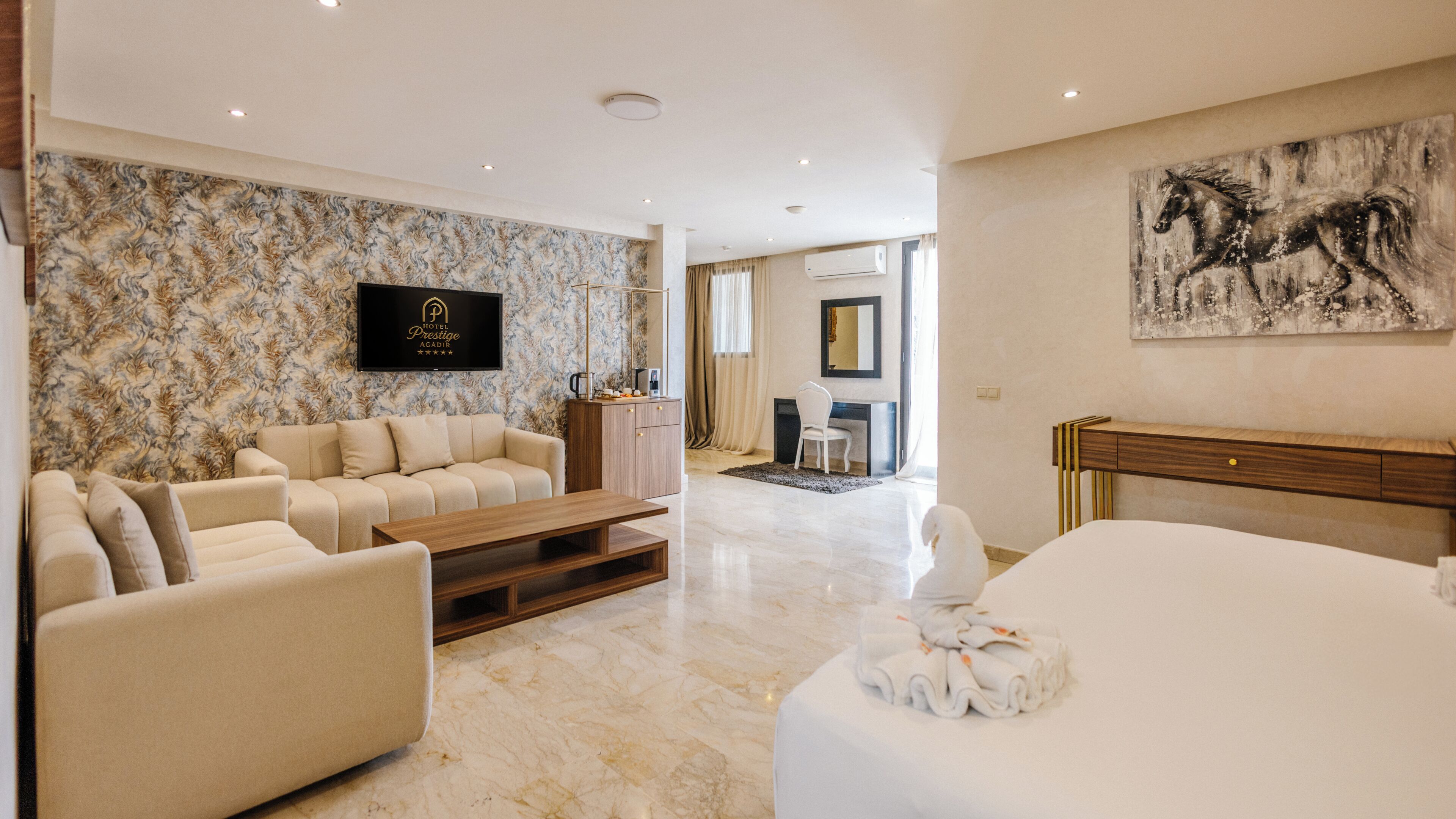 A hotel room with a marble floor, a sofa, a bed, a TV, a desk, and a painting.