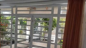 Un salón con sofá, un tapete estampado y vistas a un patio exterior con mesa y sillas.