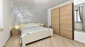 Ein Schlafzimmer mit Bett, Nachttischen, einem Kleiderschrank und einem Spiegel.