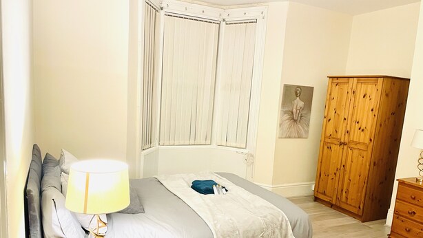 Ein Schlafzimmer mit Bett, Nachttisch, Nachttischlampe, Telefon, Kleiderschrank und einem Bild an der Wand.