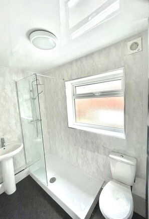 Une salle de bain moderne avec une douche à parois de verre, des toilettes et un lavabo.