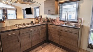 A modern kitchen with a gas stove, stainless steel sink, and wooden cabinets. - Evergreen Pines (Scarborough)