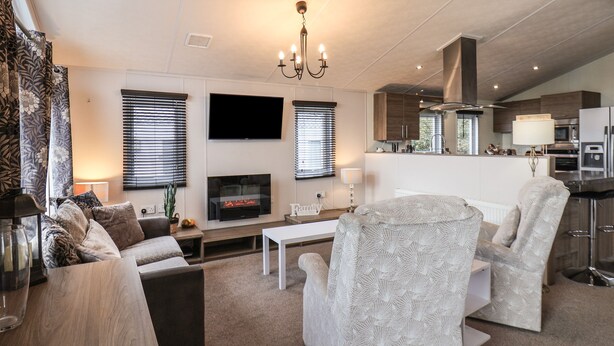 A modern living room with a fireplace, sofa, armchair, and a flat-screen TV. - Evergreen Pines (Scarborough)
