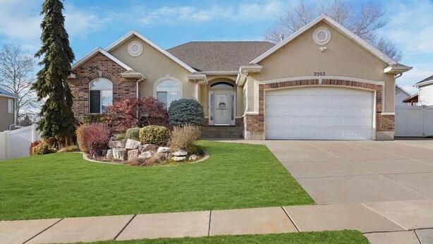 A two-story house with a brick facade, a front garage, and a well-maintained lawn.