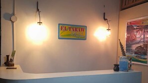 Ein Empfangsbereich mit einem Schild für 'EL TARAW Bed & Breakfast' und einem Poster von 'Puerto Princesa'.