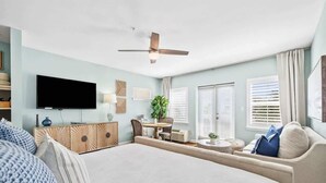 A spacious bedroom with a large bed, a ceiling fan, a TV, a dining area, and a sofa. - AviaVista | Gulf Views, Steps to Private Beach (Santa Rosa Beach)