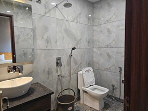 A bathroom with a marble wall, a sink, a toilet, and a shower. - Devrana (Khatoli)