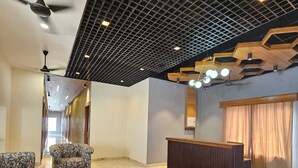 A modern lobby with patterned sofas, a reception desk, and a ceiling with a geometric design. - Devrana (Khatoli)