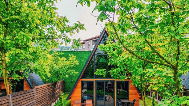 Ein modernes Haus mit Swimmingpool, Holzterrasse und kleinem Garten.