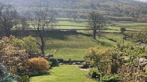 A rural landscape with rolling hills, a grassy field, and a stone wall. - Stunning 3 bed Yorkshire Dales cottage (Skyreholme)